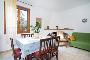 Un comedor con una mesa, sillas, una planta en maceta, un sofá y una chimenea.