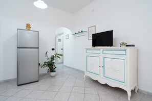 Cozinha com geladeira, televisão e armário com gavetas.