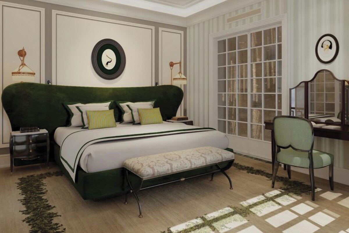 A bedroom with a large bed, a bench, a desk, and a chair.