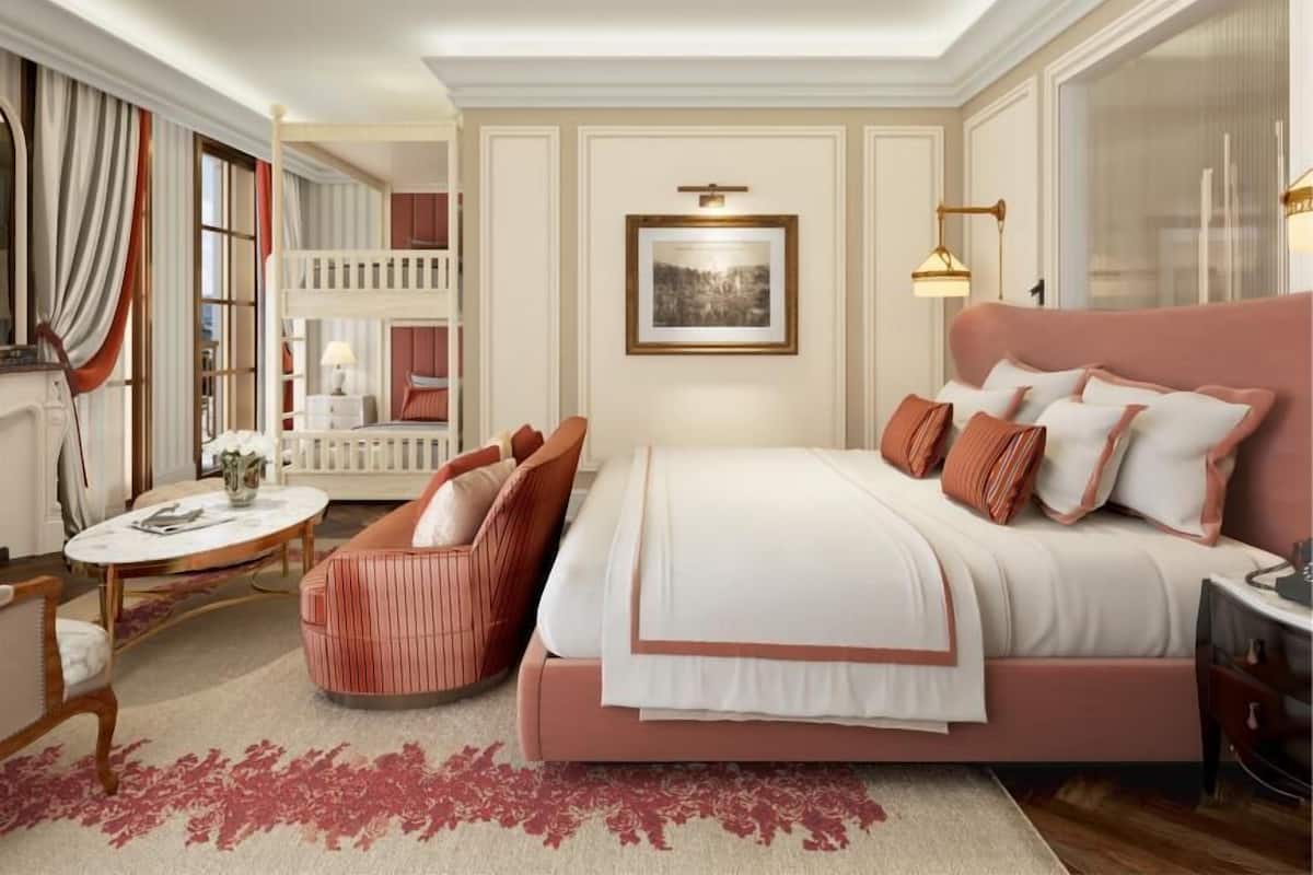 A bedroom with a large bed, a chair, a desk, and a window.