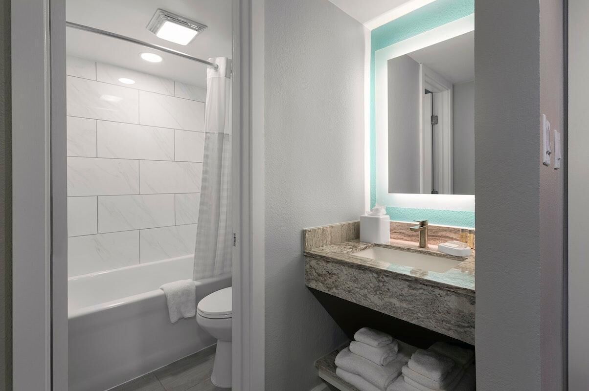 A bathroom with a bathtub, toilet, and a sink with a marble countertop.