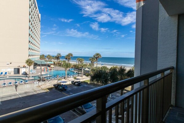 Ein Hotelbalkon mit Blick auf Strand, Pool und Palmen.