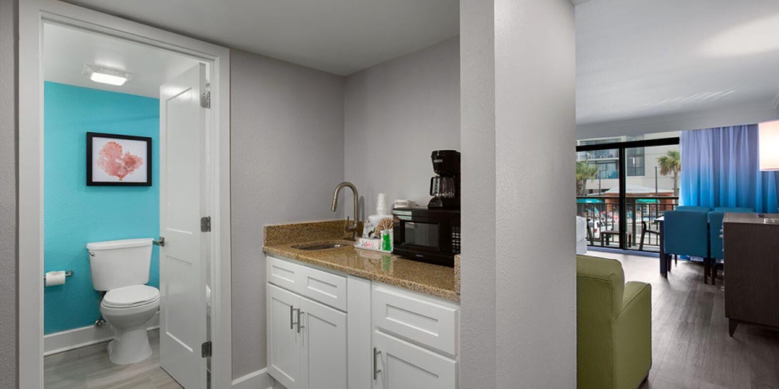 A modern bathroom with a toilet, sink, and coffee maker.