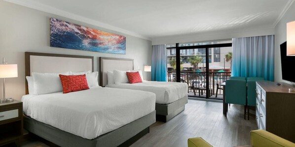 A hotel room with two beds, a desk, a TV, and a balcony with a view of the city.