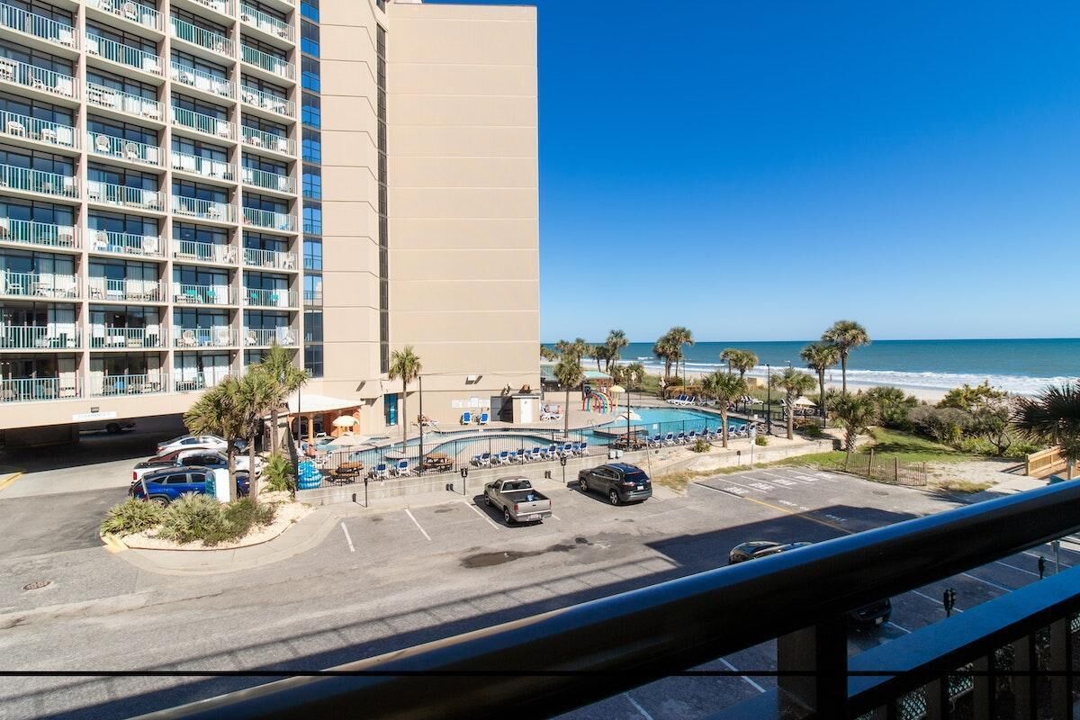 A hotel with a pool, beach view, and parking area.