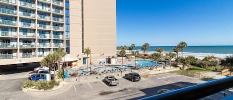 Un hotel con piscina, vistas a la playa y zona de estacionamiento.