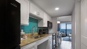 Una cocina moderna con armarios blancos, un refrigerador negro y un salpicadero verde azulado.