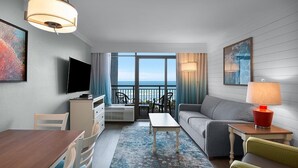 Une chambre d’hôtel moderne dotée d’un balcon, d’une télévision à écran plat, d’un coin repas et d’un canapé.