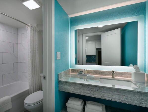 Un baño con una bañera blanca, un inodoro y un lavamanos con espejo.