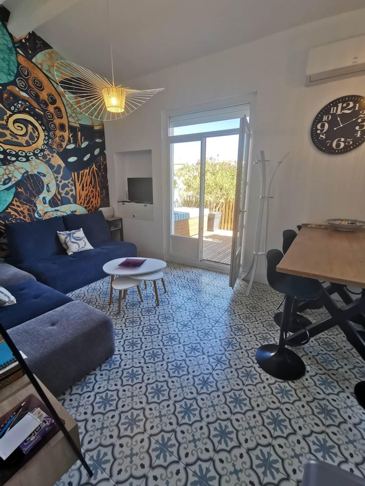 Una sala de estar con sofá, una mesita redonda, televisor y un comedor con mesa y sillas.