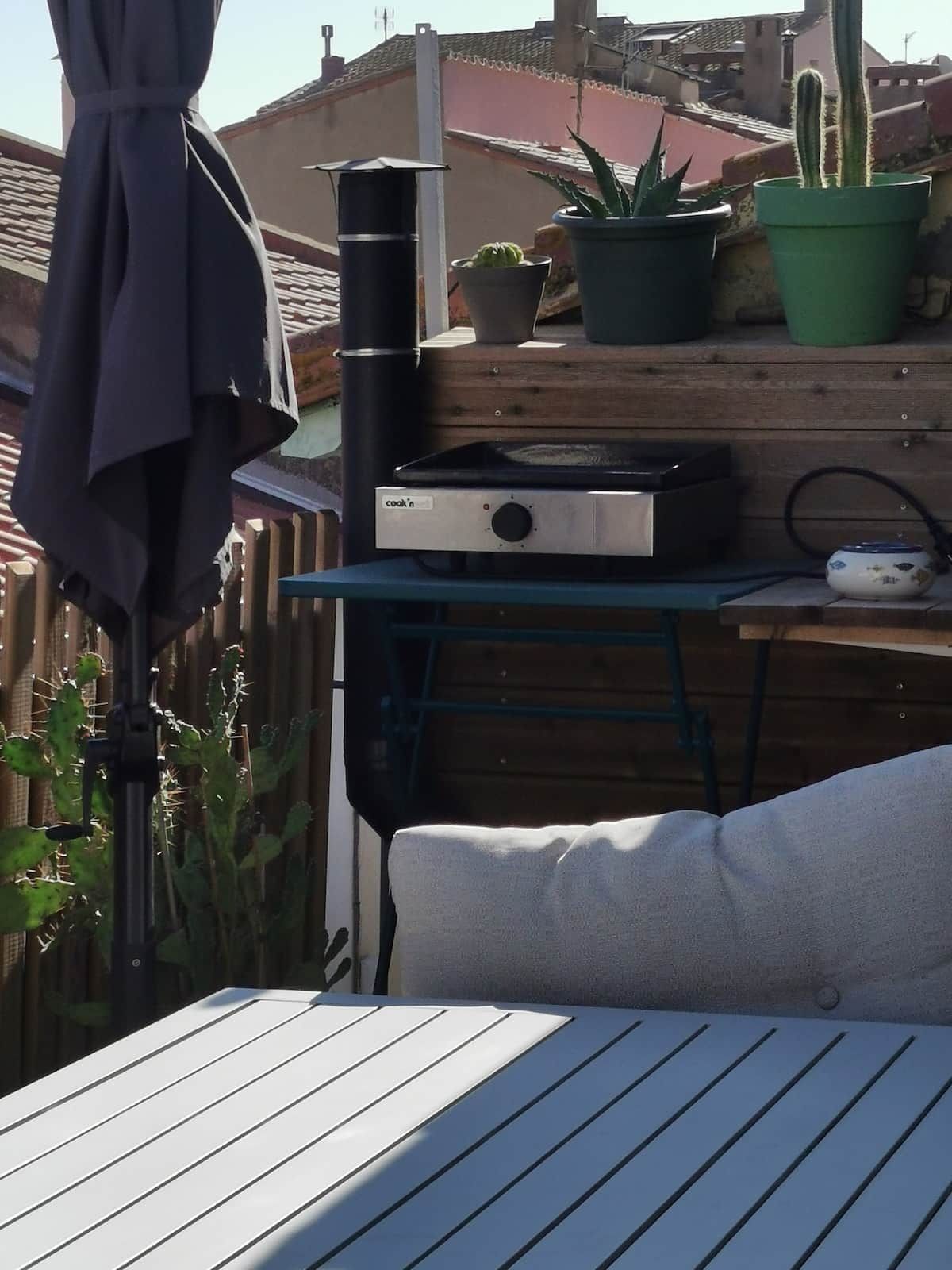 Un patio con una mesa, una parrilla y plantas en macetas.