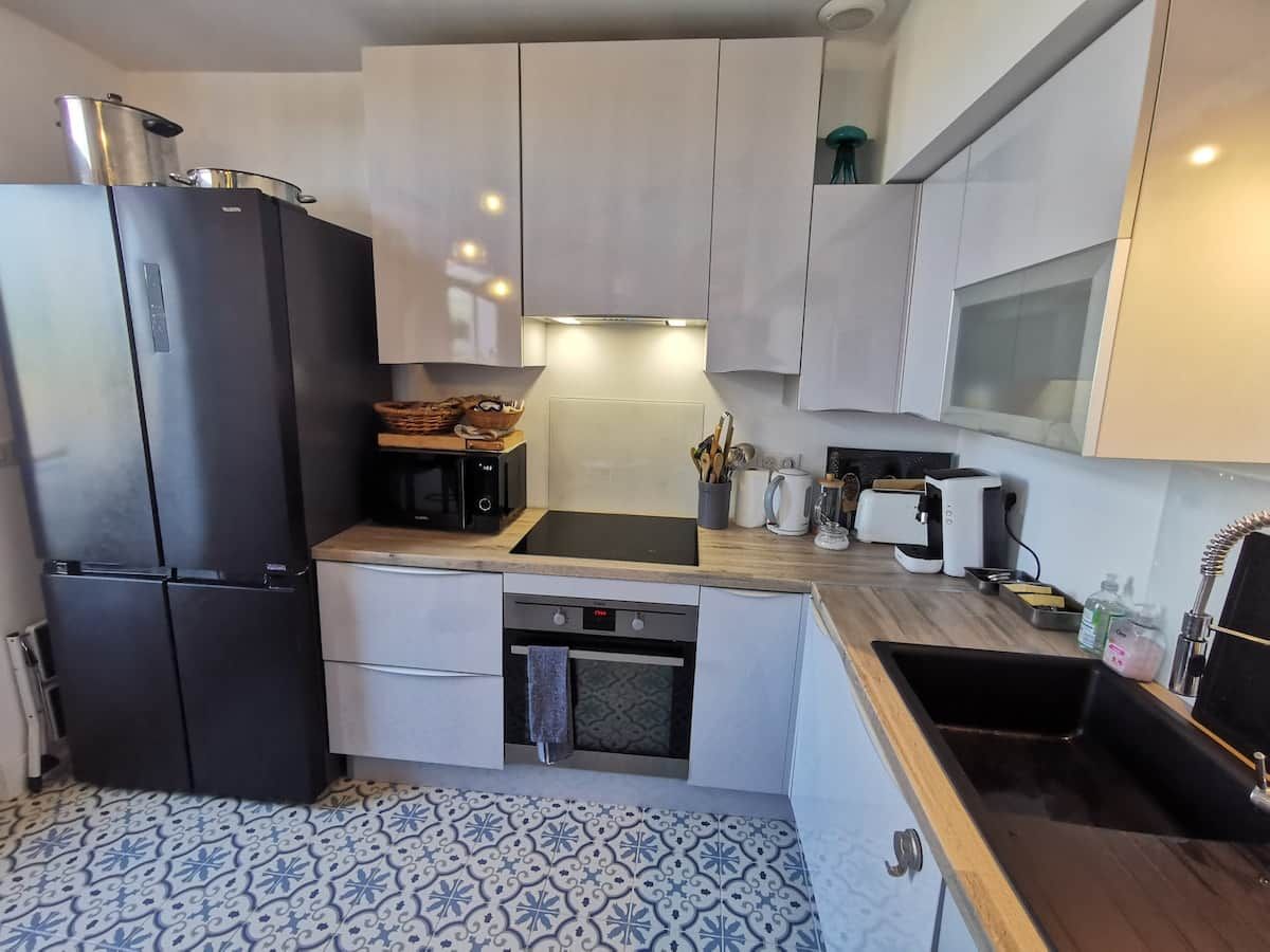 A compact kitchen with a black refrigerator, a built-in oven, and a sink.