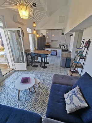 A modern living space with a sofa, a dining table, and a kitchen area.