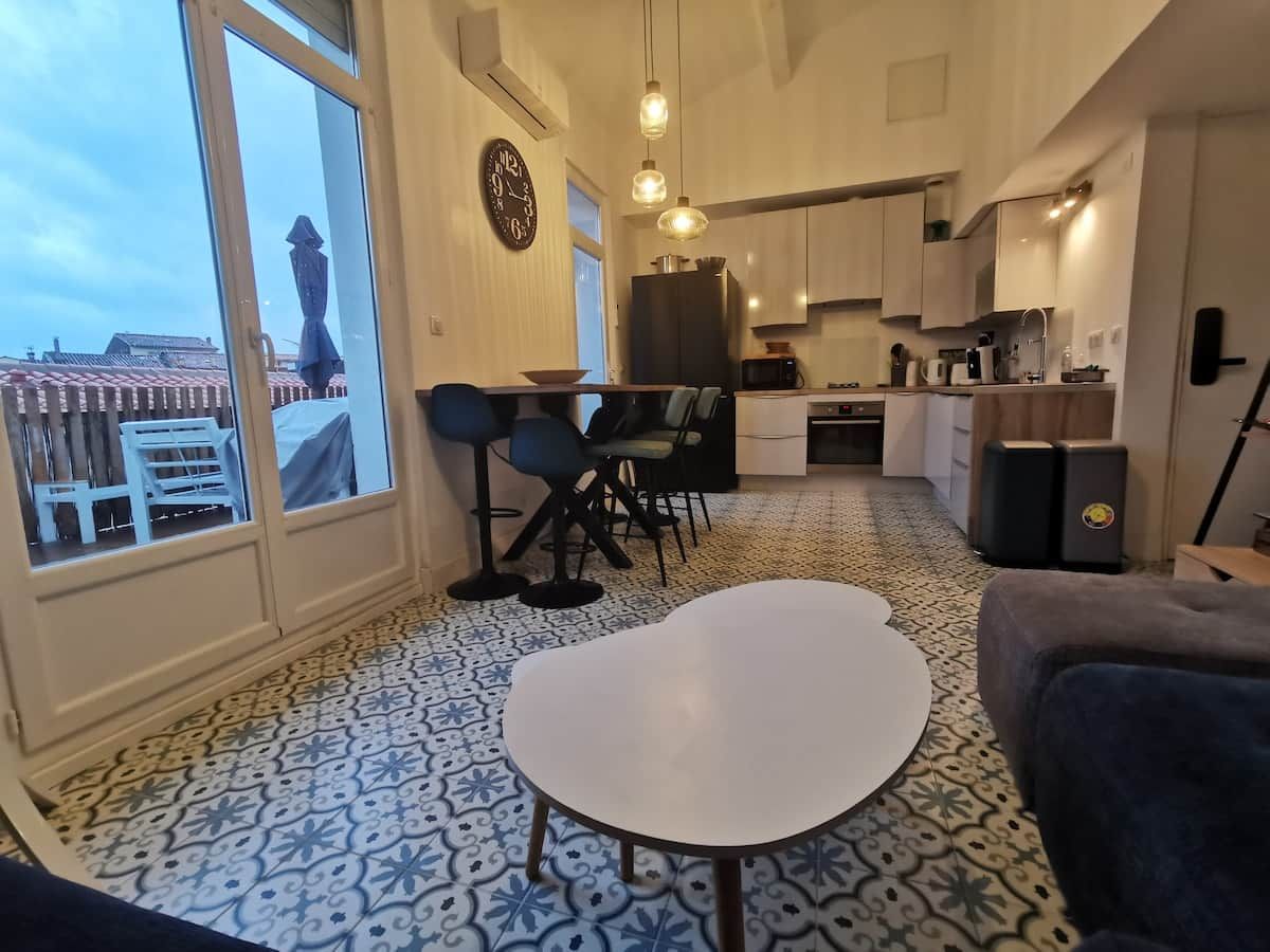 Un espacio habitable compacto con comedor, cocina y ventanas amplias que ofrecen vistas al exterior.