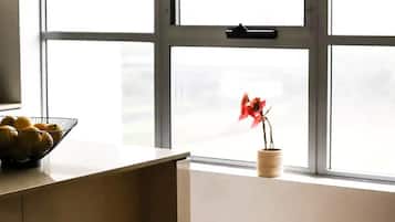 A kitchen with a large window, a bowl of lemons, a stool, and a potted plant.