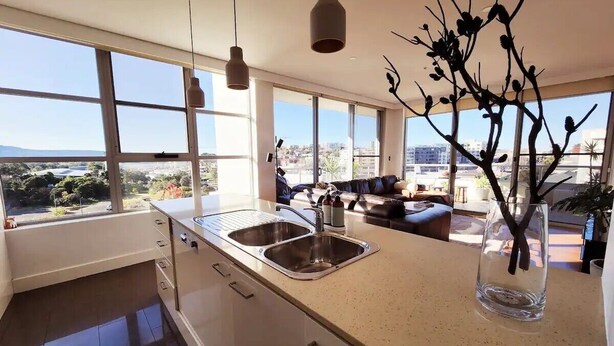 Una cocina moderna con ventanas amplias, un lavamanos y un comedor con sofá.