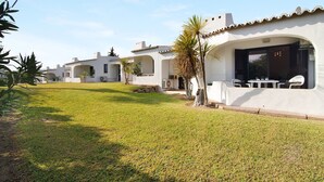 Une rangée de villas blanches dotées d’entrées en arc de cercle, une pelouse verdoyante et des espaces de détente en plein air.