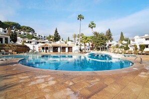 Ein Pool mit Liegestühlen, ein Restaurant und weiße Gebäude mit Bäumen.