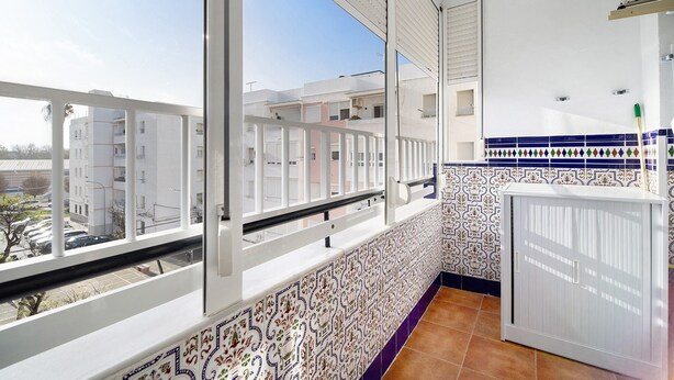 Un balcon donnant sur les immeubles voisins, un pare-feu en carreaux et une armoire blanche.