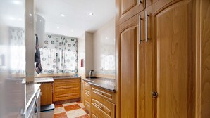 Une cuisine avec des meubles de rangement en bois, un carrelage à motifs et une fenêtre ornée de rideaux à motifs.