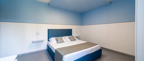 A modern bedroom with a bed, bedside tables, and a blue accent wall.
