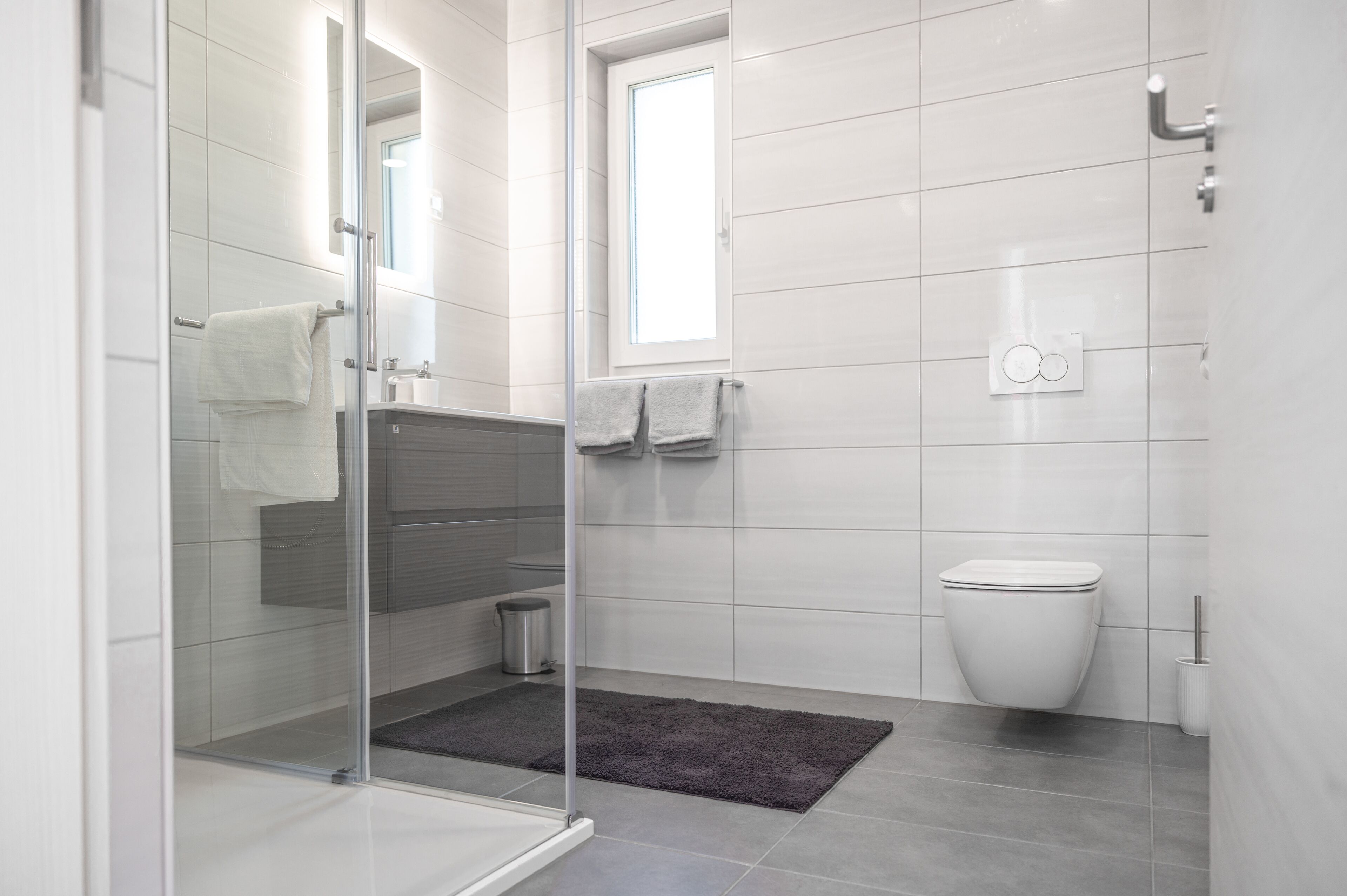 A modern bathroom with a glass shower enclosure, a toilet, and a sink.