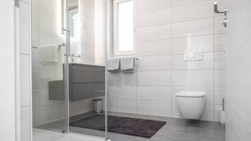 A modern bathroom with a glass shower enclosure, a toilet, and a sink.