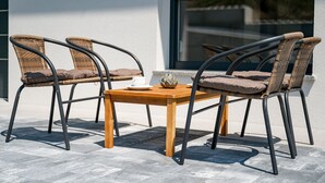 A wooden table with two wicker chairs, a white cup, and a decorative bowl.