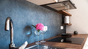 A modern kitchen with a stainless steel faucet, a wooden countertop, and a vase with pink flowers.