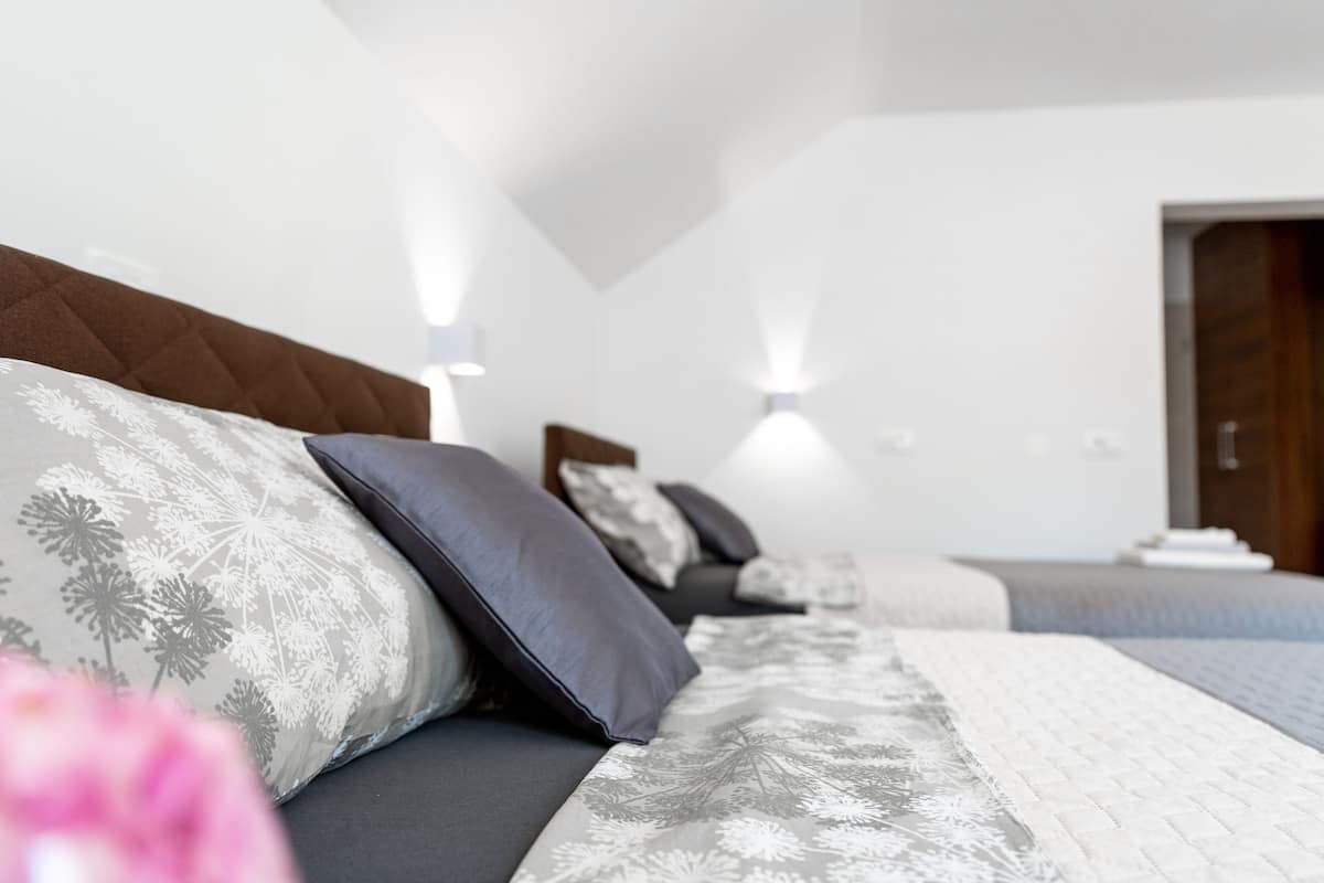 A modern bedroom with a large bed, a wooden headboard, and two bedside lamps.