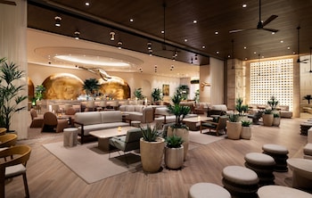 A modern room with a large window, a comfortable armchair, a small table with a bottle, and a lamp. at Durango Casino & Resort