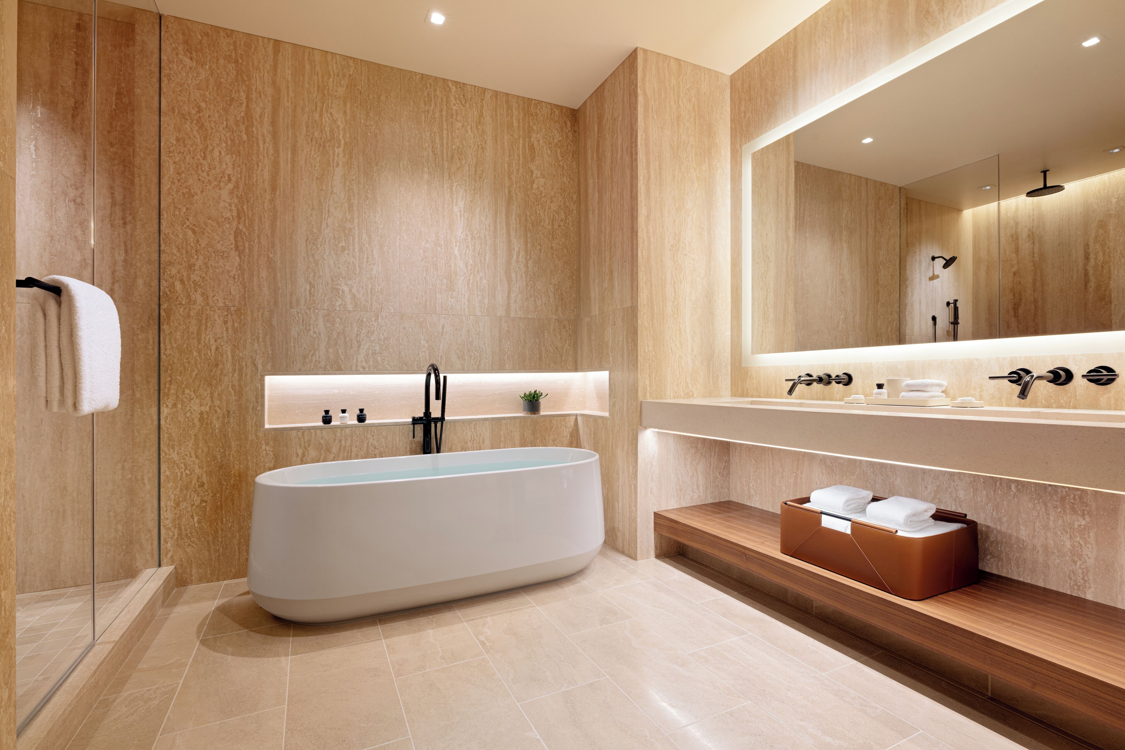Une salle de bain moderne avec une baignoire sur pieds, un grand miroir et un meuble-lavabo en bois doté d’un porte-serviettes.