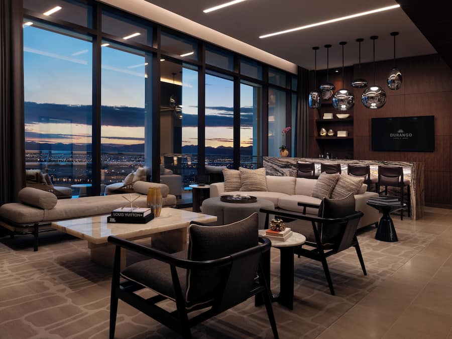 A modern living room with a large window, a sofa, chairs, a coffee table, and a TV.