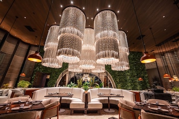 A spacious lobby with a modern design, featuring a seating area with sofas and chairs, a bar area, and a large decorative wall. at Durango Casino & Resort