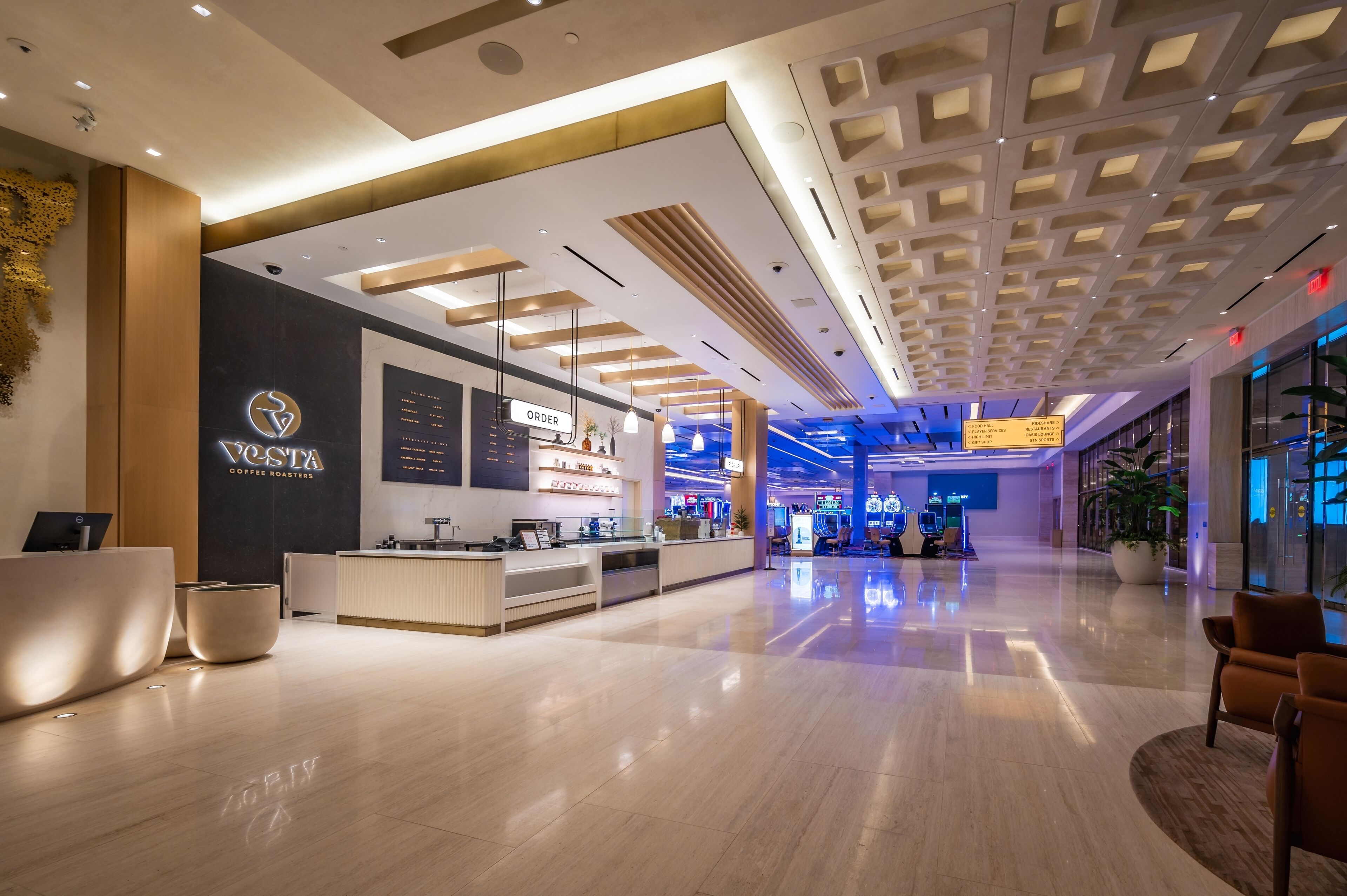 A modern coffee shop with a sleek design, featuring a reception area, seating, and a menu board.