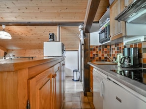 A kitchen with wooden cabinets, a refrigerator, a microwave, and a coffee maker.
