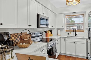 Una cocina moderna con gabinetes blancos, electrodomésticos de acero inoxidable y salpicadero a cuadros.