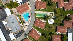 An aerial view of a residential area with multiple houses, a swimming pool, and a tennis court.