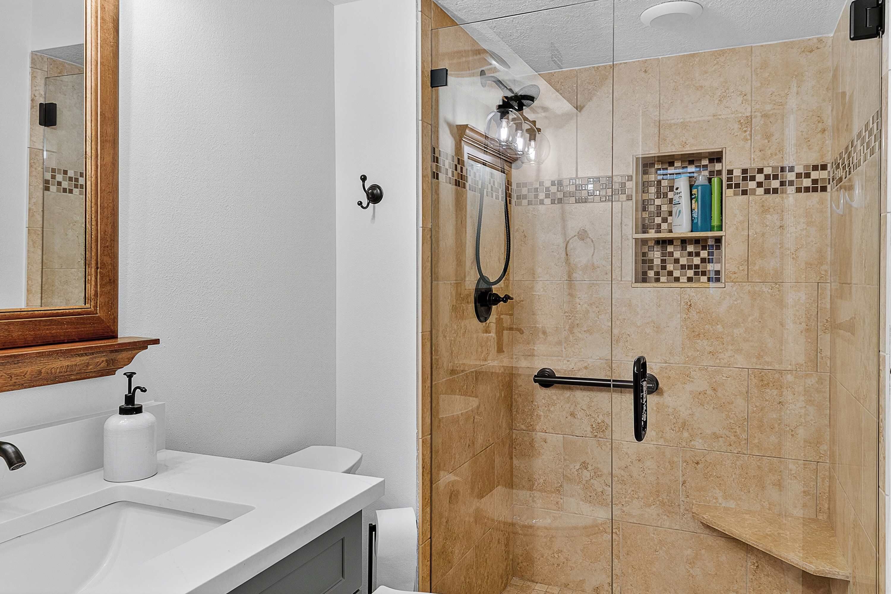 A bathroom with a shower, a sink, and a mirror.