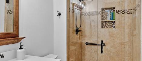 A bathroom with a shower, a sink, and a mirror.