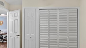 A hallway with a closed white door and a white louvered closet. - Coastal Paradise Condo  (Siesta Key)