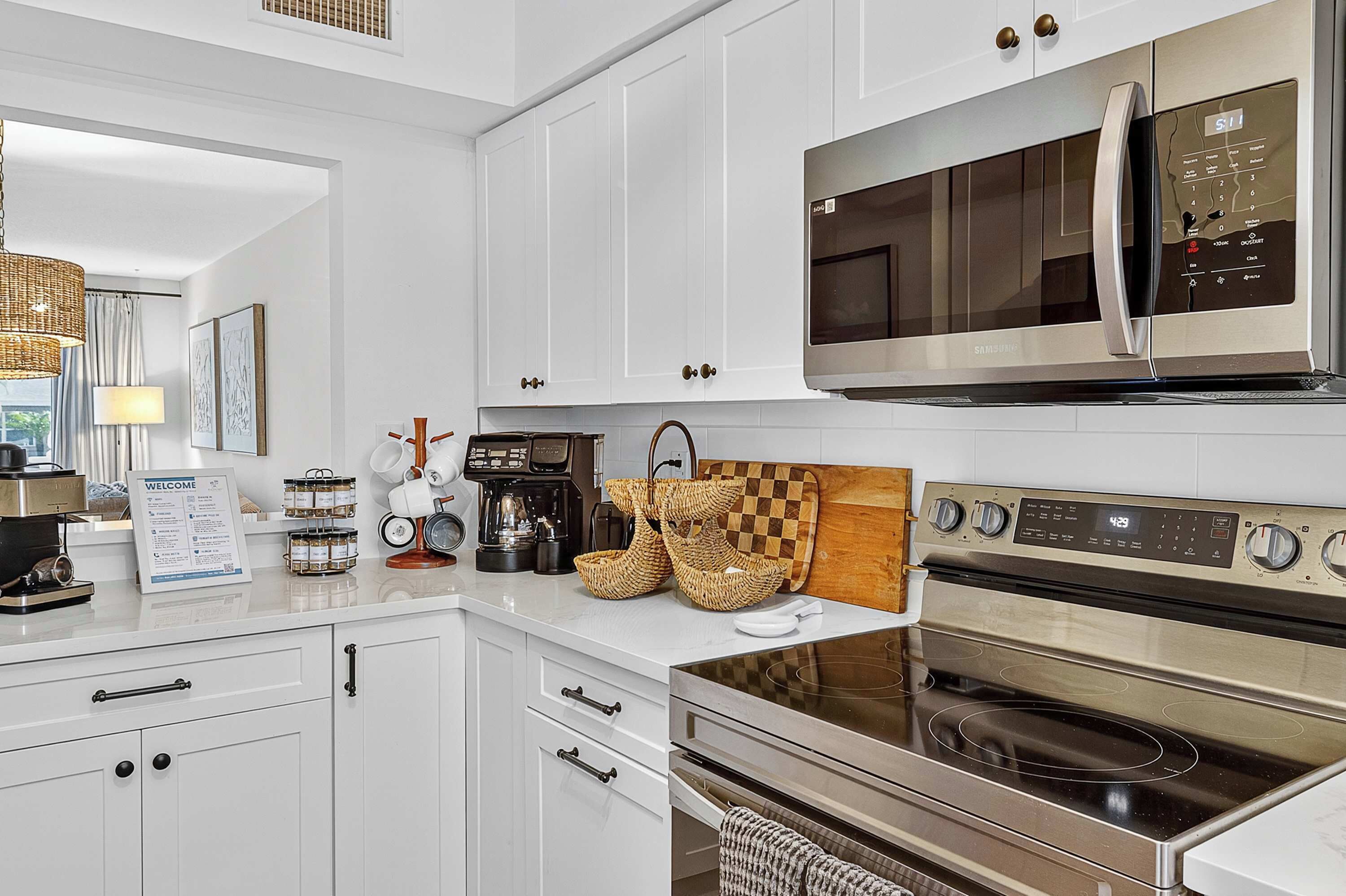 A modern kitchen with white cabinetry, stainless steel appliances, and a digital clock.