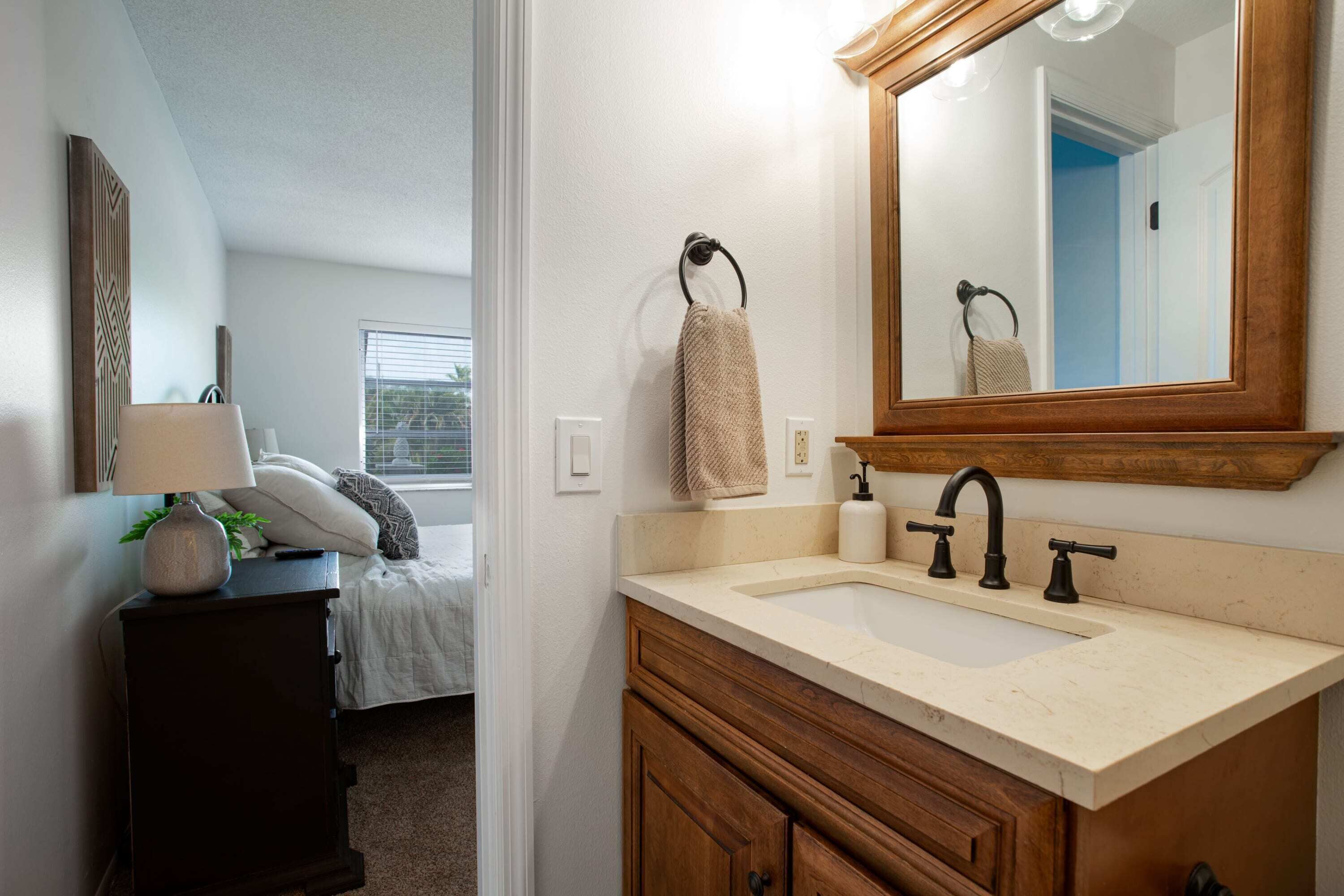 A bathroom with a wooden vanity, a sink, a mirror, and a towel rack.