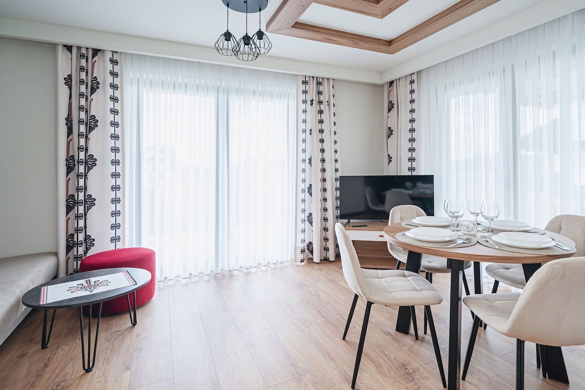 Un salon moderne comprenant un coin repas, un téléviseur à écran plat et un canapé.