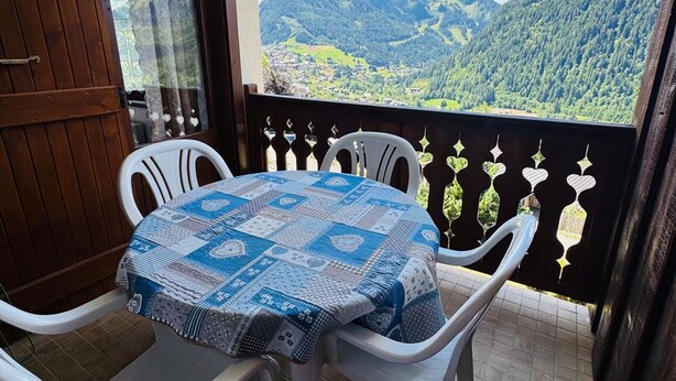A balcony with a table and chairs, overlooking a mountainous landscape. - Charming 3-Room Apartment in Châtel - Pets Allowed & Parking (Châtel)