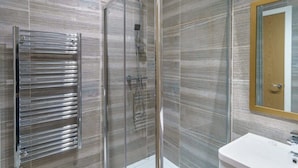 A modern bathroom with a glass-enclosed shower, a chrome towel rack, and a white sink. - Bright 2 Bedroom Apartment in Central Manchester (Manchester)