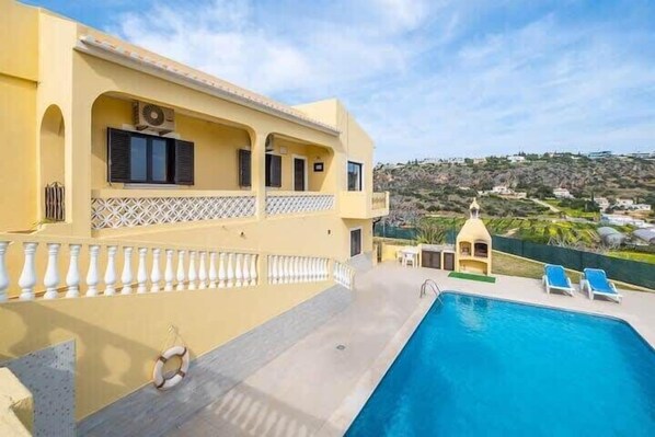 Un espace aménagé au bord de la piscine offrant une vue dégagée sur une colline.