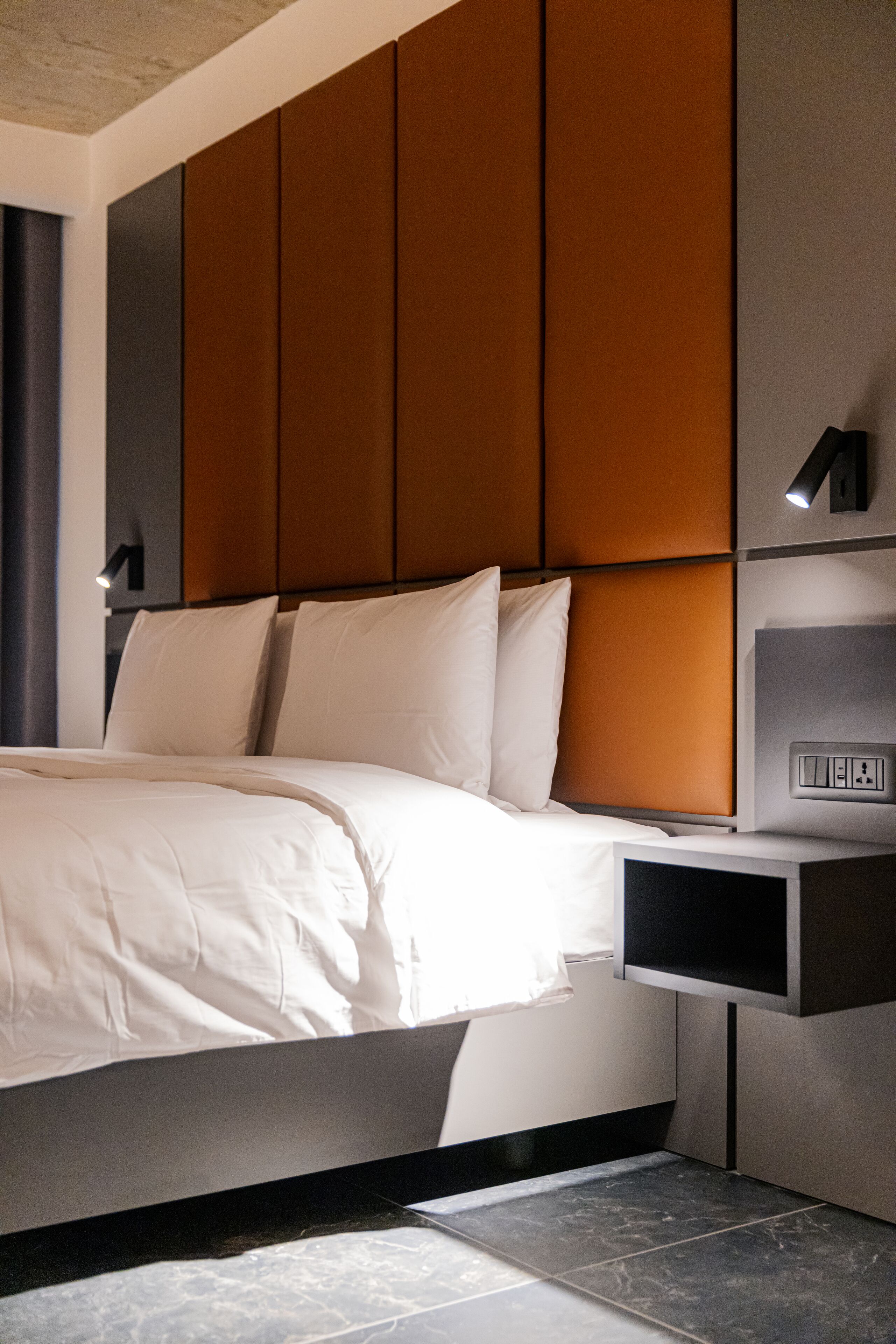 Ein modernes Schlafzimmer mit einem großen Bett, einem Nachttisch und einer Wandleuchte.