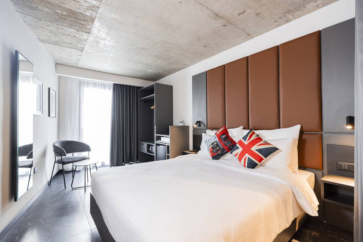 Una habitació d'hotel moderna amb un llit gran, un escriptori, una cadira i un armari.