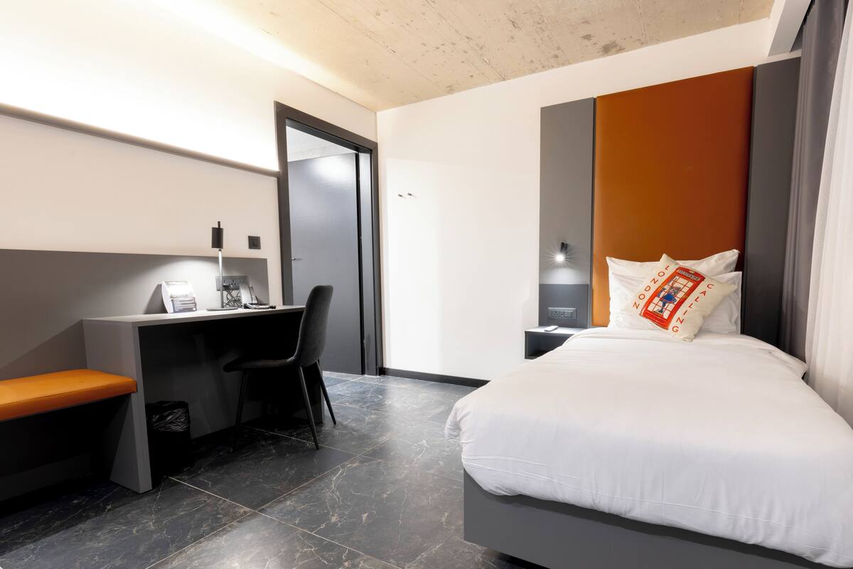 Habitació d'hotel moderna amb un llit, una taula de treball i una cadira.